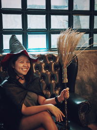 Portrait of smiling young woman holding while sitting outdoors