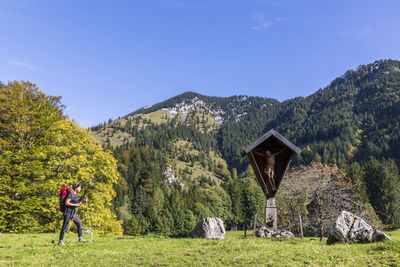 People walking on field against mountain