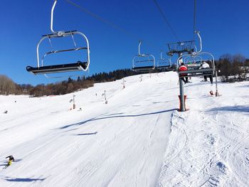 Ski lift over snow covered field against sky