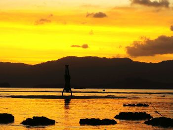 Silhouette man by lake against sky during sunset