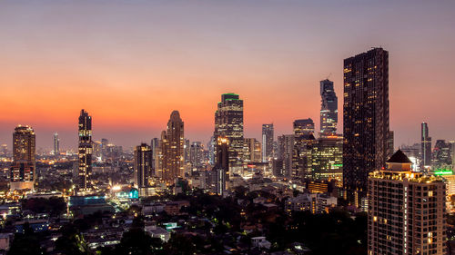 Illuminated cityscape against sky during sunset