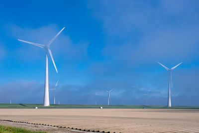 Wind turbines on field against sky