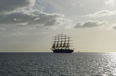 Sailboat sailing in sea against cloudy sky during sunny day