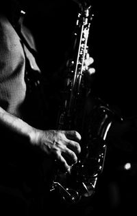 Close-up of man playing guitar against black background