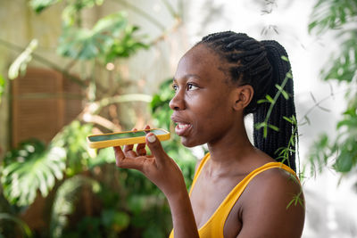 Side view of young woman blowing bubbles while standing outdoors