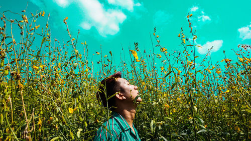 Man amidst blooming flowers against blue sky