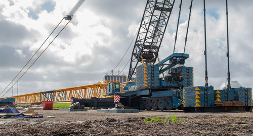 Low angle view of crane at construction site against sky