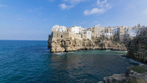 Buildings by sea against blue sky