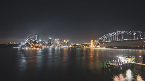 Illuminated bridge over river at night