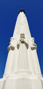 Low angle view of cross against building against clear blue sky