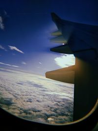 Airplane wing against sky seen through window