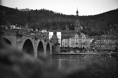 Bridge over river by buildings in city against sky