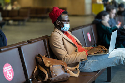 Side view of man wearing hat sitting on seat