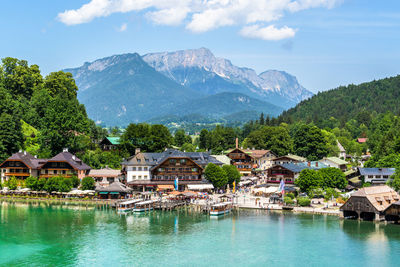 Houses by swimming pool by lake and mountains against sky