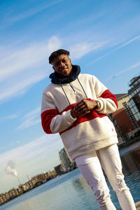 Man standing by sea against sky in city