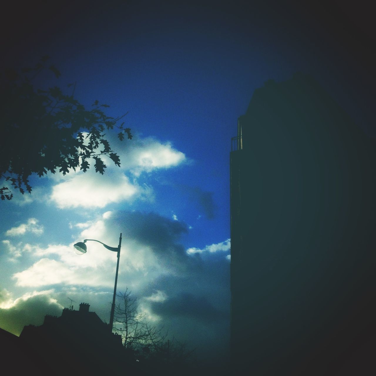 building exterior, architecture, built structure, sky, low angle view, cloud - sky, silhouette, city, building, cloud, tower, cloudy, tall - high, dusk, skyscraper, tree, outdoors, no people, blue, office building