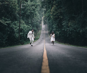 Rear view of people walking on road amidst trees