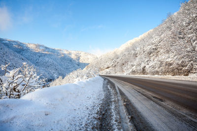 Road amidst snowcapped mountains against sky