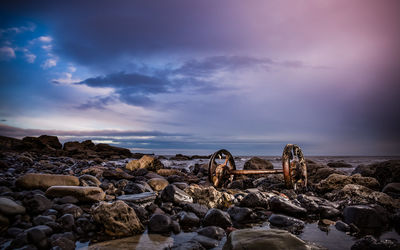 Rocks on beach against sky during sunset