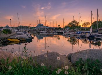 Sailboats moored at harbor during sunset