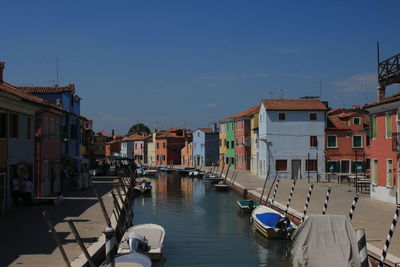 Boats moored in canal amidst buildings in city