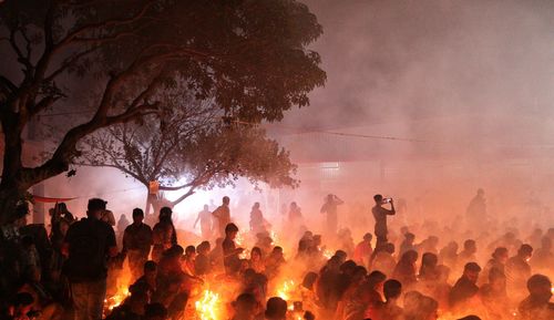 People are praying at rakher upobash under big tree in a smokey environment