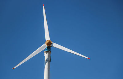 Low angle view of windmill against clear blue sky