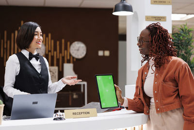 Side view of young woman using laptop while standing in office