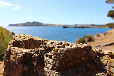 Close-up of rocks by sea against sky