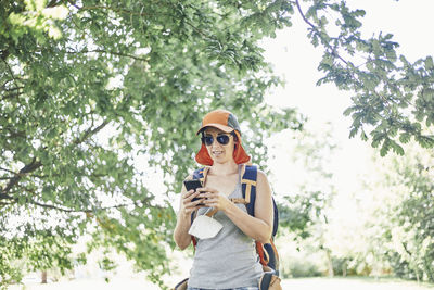 Portrait of young woman wearing sunglasses standing against plants