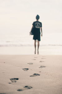 Full length rear view of woman walking on beach