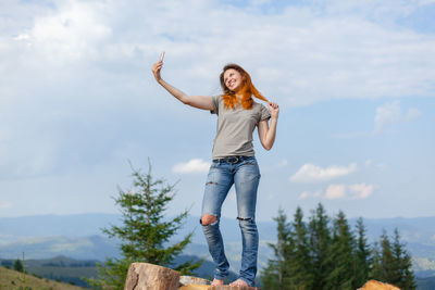 Girl makes selfie on a smartphone against the background of the carpathian mountains