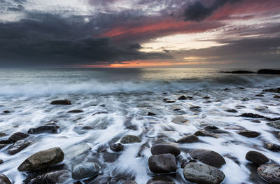 Scenic view of sea against dramatic sky during sunset