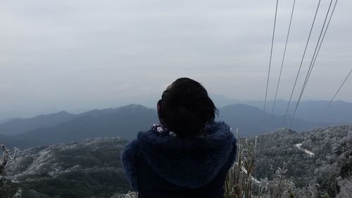 Rear view of man looking at mountains against sky