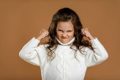 Portrait of young woman standing against yellow background