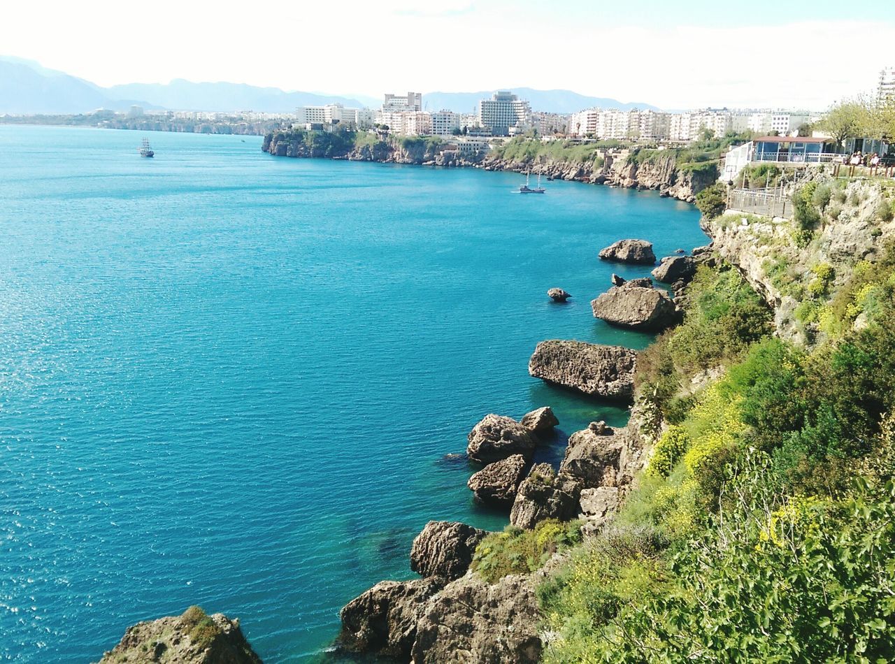 sea, water, blue, architecture, building exterior, horizon over water, built structure, high angle view, coastline, scenics, tranquil scene, tranquility, beauty in nature, rock - object, nature, cliff, sky, ocean, city, rock