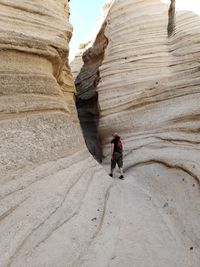 Rear view of woman walking by rock formation