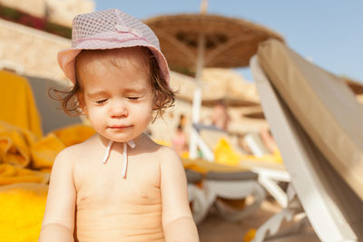 Cute shirtless girl with eyes closed wearing hat at beach