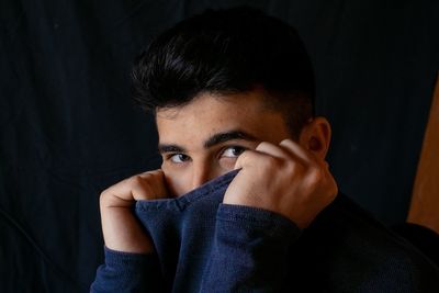 Portrait of man making face against black background