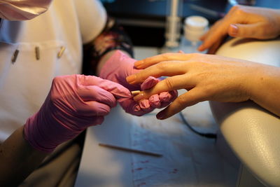 Midsection of beautician applying nail polish on female customer in salon