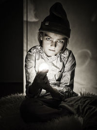 Portrait of boy holding light bulb at home