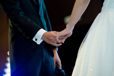 Midsection of bride and bridegroom holding hands during wedding ceremony