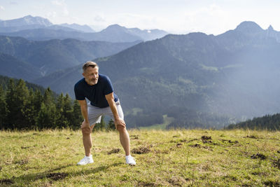 Full length of man standing on grass against mountains