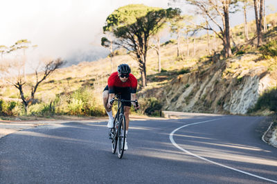 Rear view of man riding bicycle on road