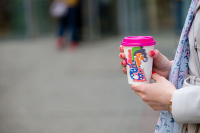 Midsection of woman holding ice cream in city