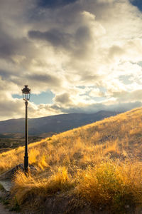 Street light on field against sky at sunset