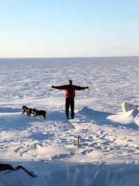 Man with dogs standing on snow covered landscape