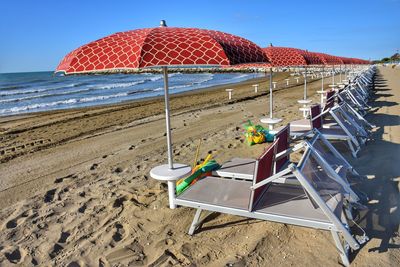 Deck chairs on beach against clear sky