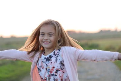 Portrait of smiling girl standing against sky