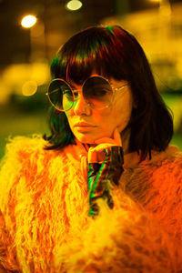 Portrait of woman wearing sunglasses and warm clothing at night